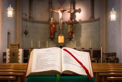 Open book of Gospels with Altar and crucifix in background