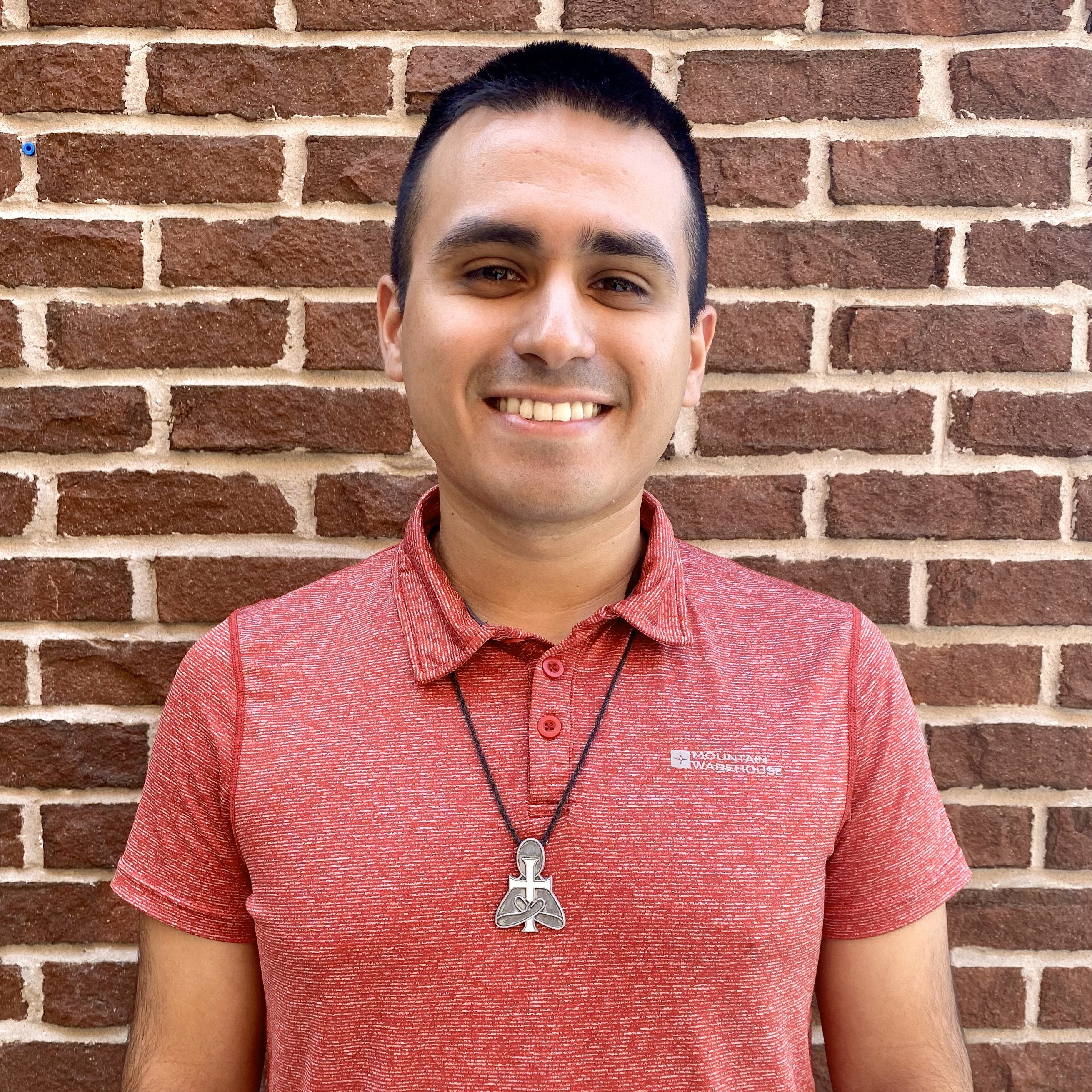 Picture of young man in front of a brick red wall