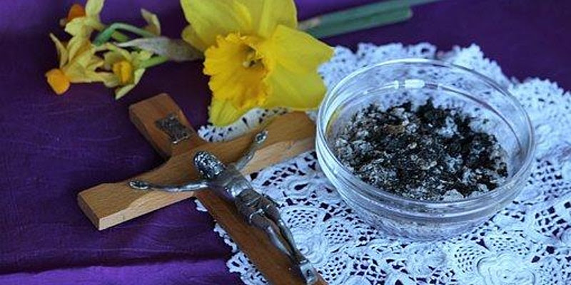 Crucifix, bowl of ass and flowers on a purple table